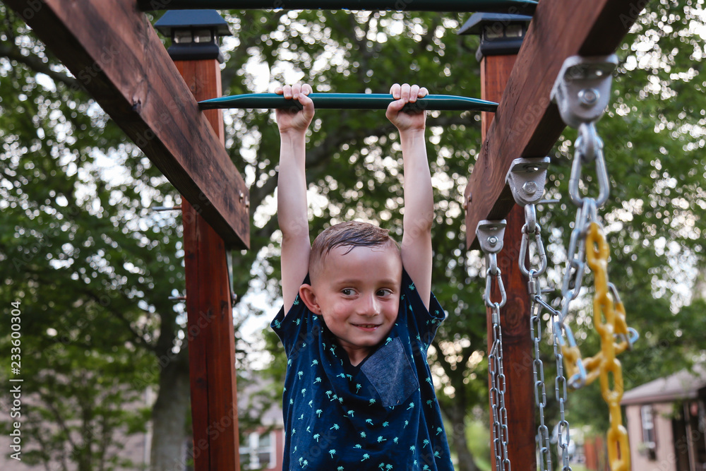 Fototapeta premium Young Child Swinging on the Monkey Bars Smiling