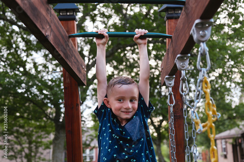 Young Child Swinging on the Monkey Bars Smiling