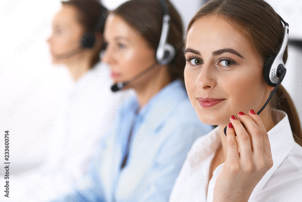 Call center. Group of operators at work. Focus at beautiful business woman in headset Call center. Group of operators at work. Focus at beautiful business woman in headset