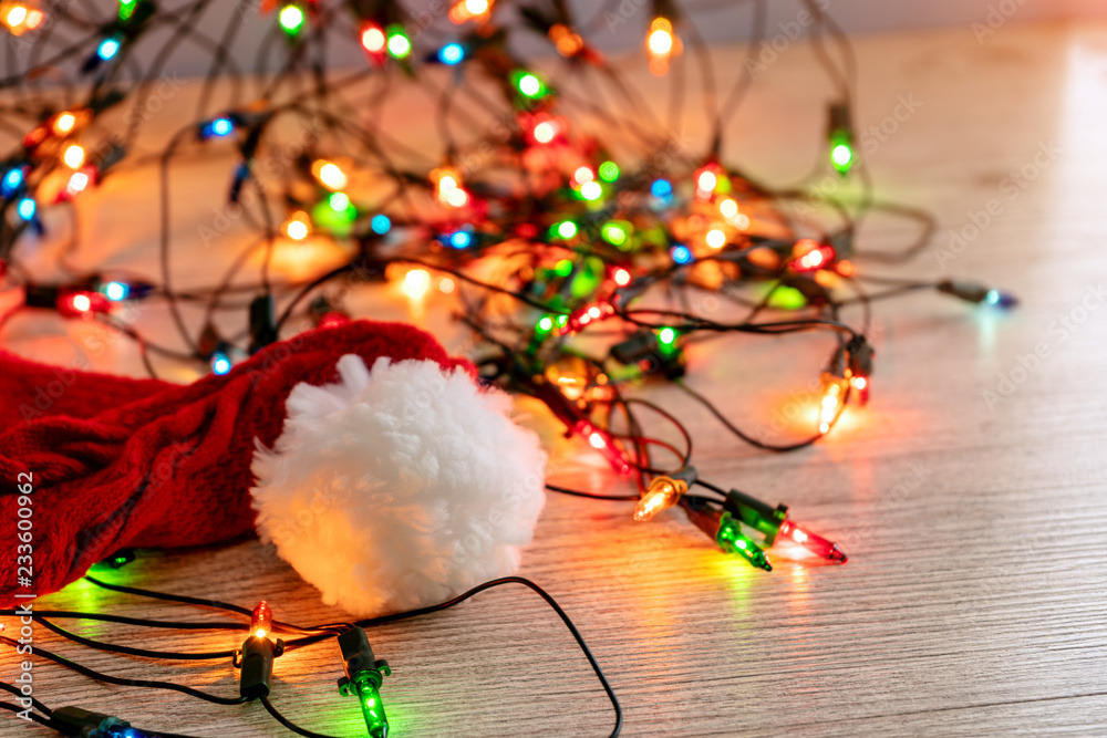 New year's red knitted cap with white pompom on the background of lights garland