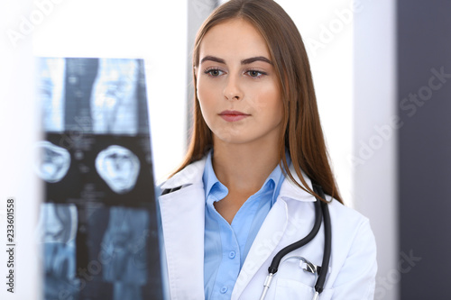 Doctor woman examining x-ray picture while standing near window in hospital. Surgeon or orthopedist at work. Medicine and healthcare concept photo