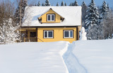 Yellow wooden house with terrace and snowman on forest background in winter sunny day
