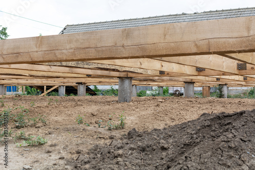 Pile foundation frame house. Piles of concrete and the base of the floor of a wooden house.