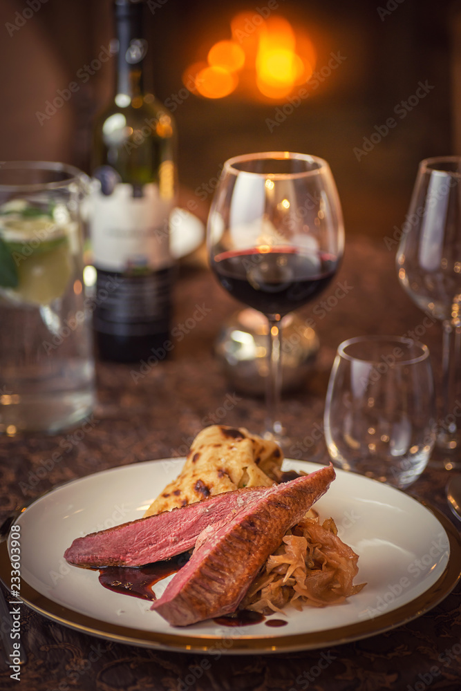 roasted duck breast with cabbage and pancake served on white plate with glass of wine, winter and seasonal food, product photography for restaurant