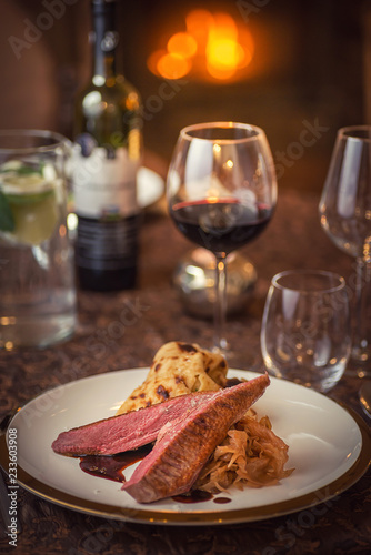 roasted duck breast with cabbage and pancake served on white plate with glass of wine, winter and seasonal food, product photography for restaurant