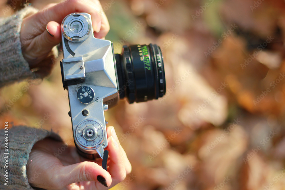 Fototapeta premium Vintage camera in hand on blurred background. Close-up, focus on camera controls