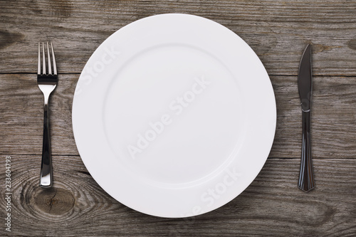 Empty white ceramic plate and cutlery on a village table  top view