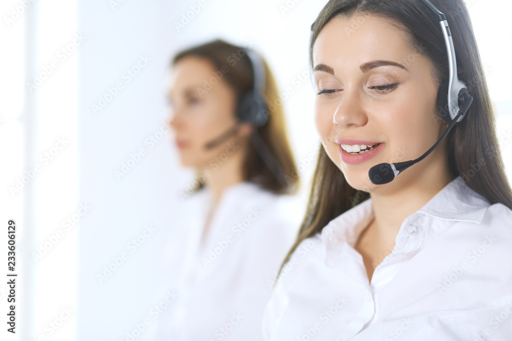 Group of call center operators at work. Focus on beautiful business woman in headset Group of call center operators at work. Focus on beautiful business woman in headset