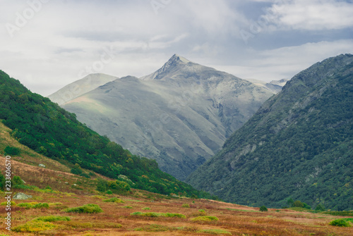 autumn mountain pass with red grass on the background of rainy mountains in the Caucasus