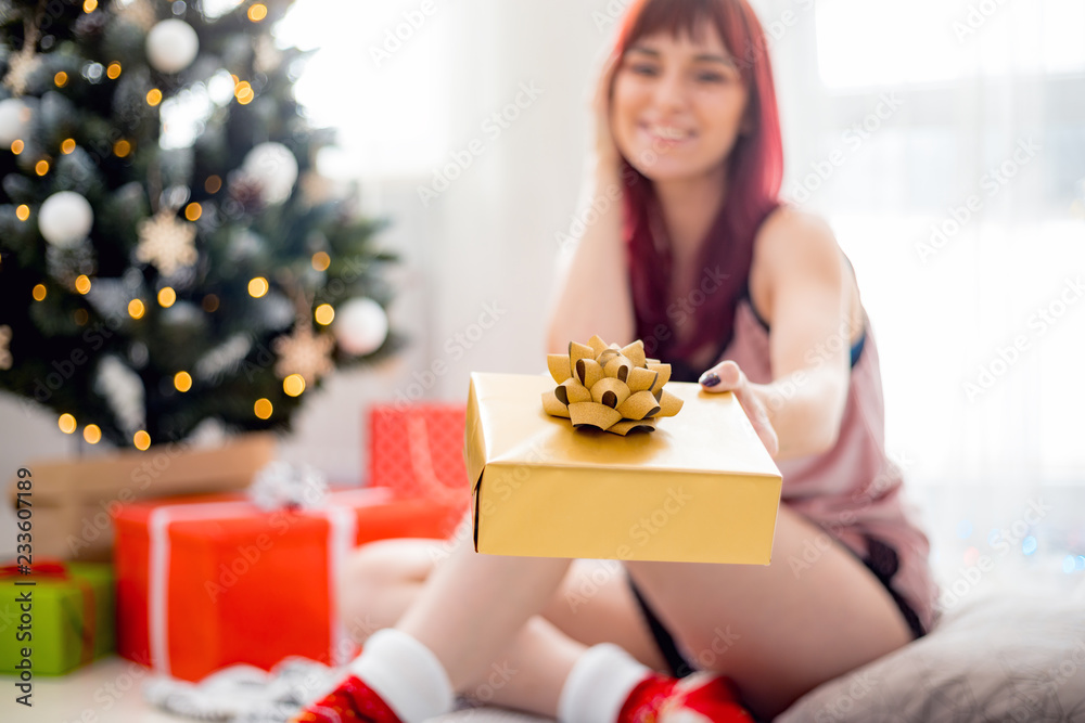 Beautiful woman in underwear giving Christmas gift box to camera Beautiful woman in underwear giving Christmas gift box to camera