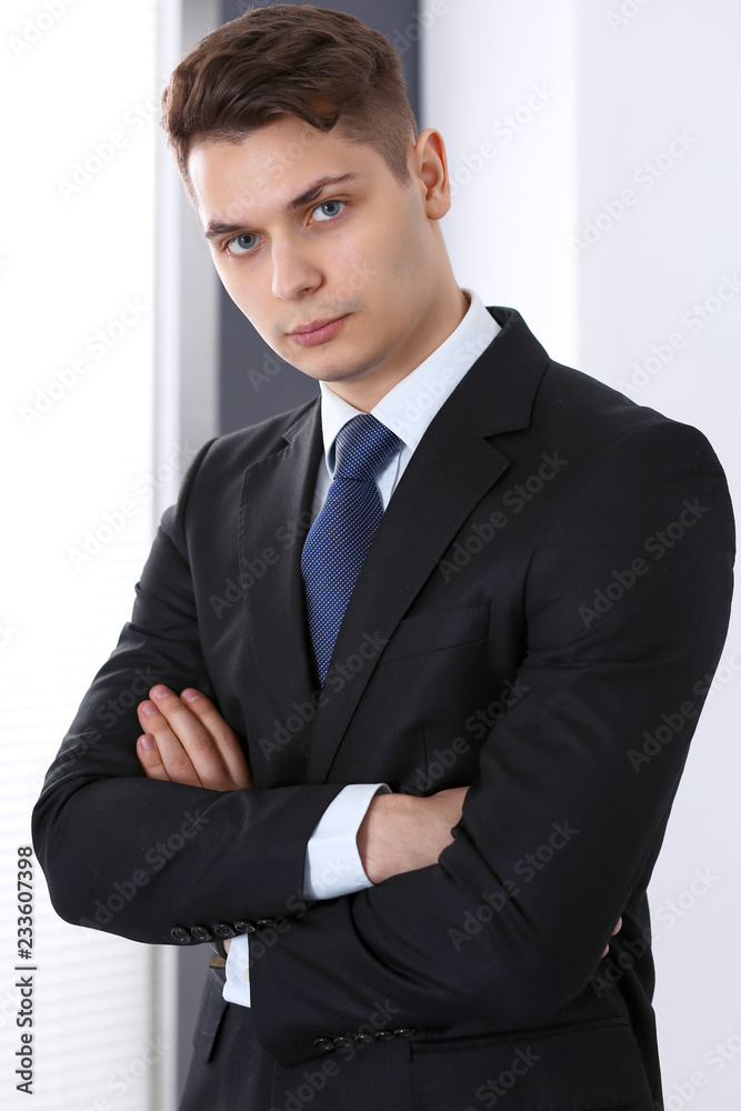 Young businessman standing in office with arms crossed. Business concept Young businessman standing in office with arms crossed. Business concept