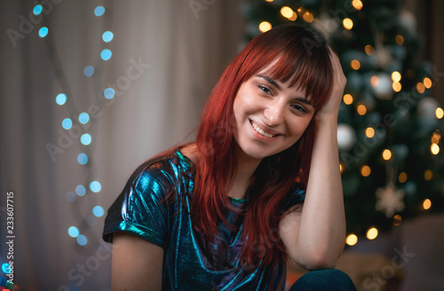 Beautiful young woman next to Christmas tree at home