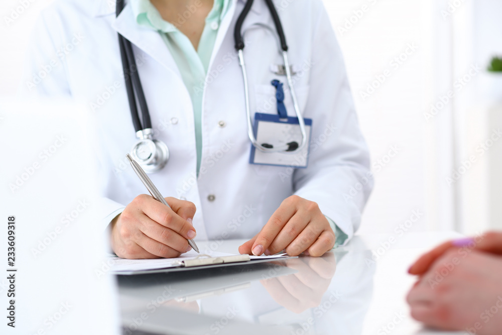 Doctor woman consulting patient while filling up an application form at the desk in hospital. Just hands close-up. Medicine and health care concept Doctor woman consulting patient while filling up an application form at the desk in hospital. Just hands close-up. Medicine and health care concept