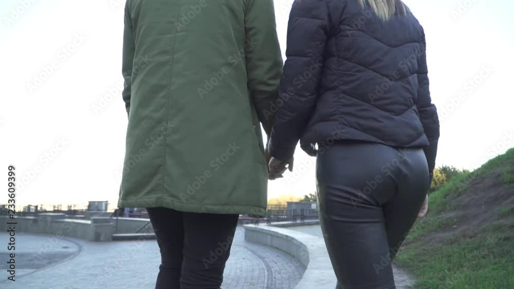 Young couple holding hands and walking outdoors. Shooting from behind. Young couple holding hands and walking outdoors. Shooting from behind.