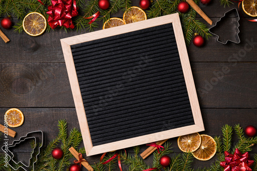 Empty  felt letter board on dark rustic wood background with Christmas decoration and fir branch frame. Top view with free text copy space