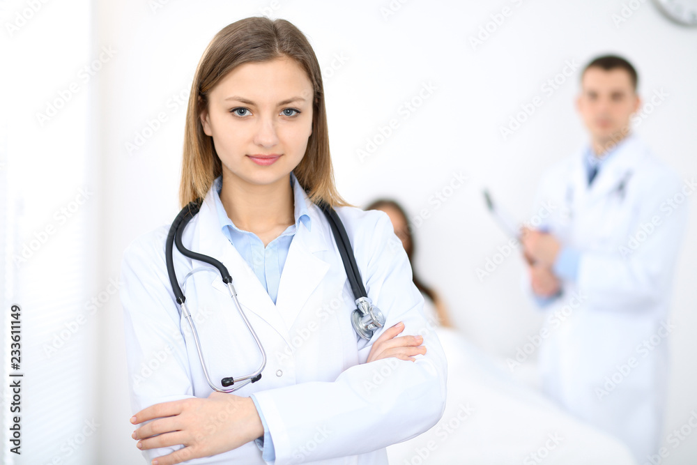 Medicine doctor standing and smiling on the background with patient in the bed Medicine doctor standing and smiling on the background with patient in the bed