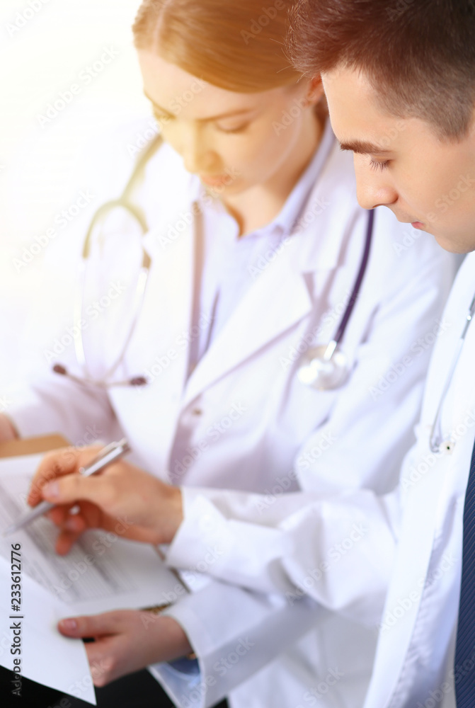 Doctors writing papers using clipboard. Physicians discussing medication program or studying at medical conference. Healthcare, insurance and medicine concept