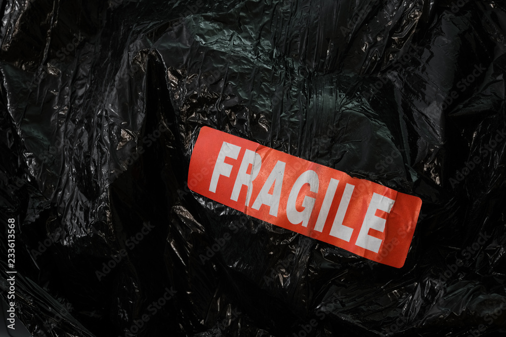 fragile emballage étiquette signalétique attention rouge emballer sac  plastique cello film noir envoyer transport Stock Photo