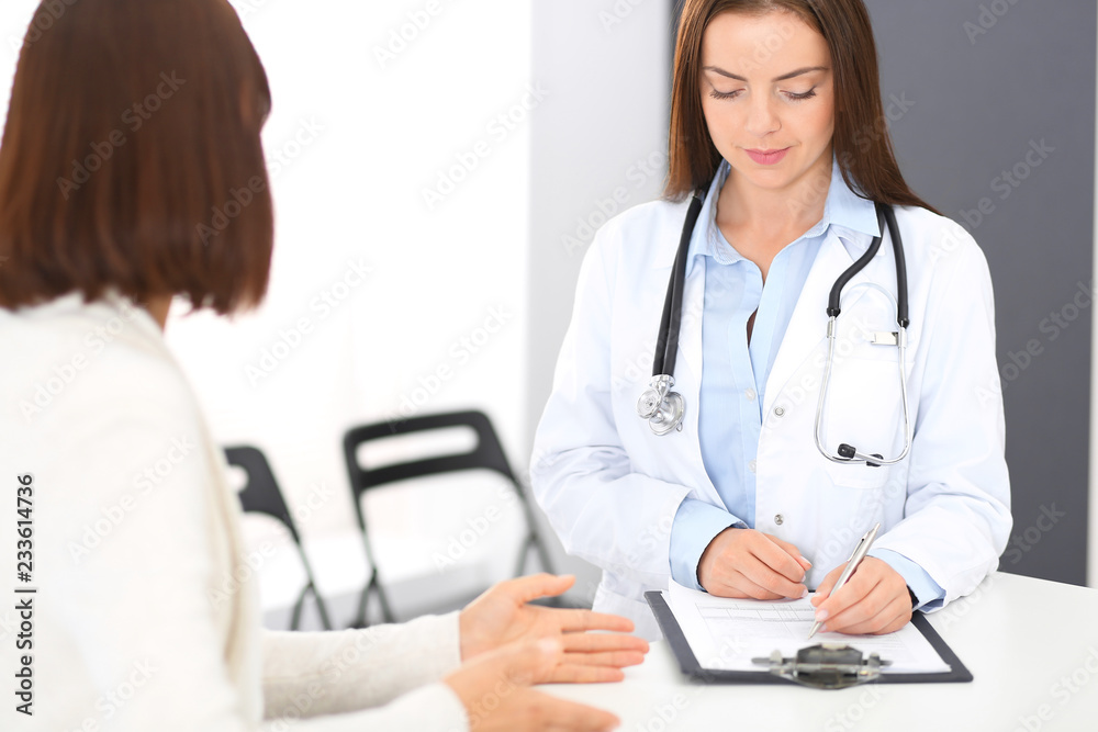 Doctor and patient discussing something while standing near reception desk in emergency hospital. Physician at work in clinic. Medicine and health care concept Doctor and patient discussing something while standing near reception desk in emergency hospital. Physician at work in clinic. Medicine and health care concept