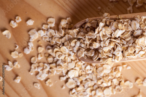 Oat flakes in a wooden bowl with a scoop on the wooden board