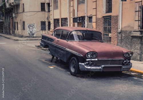 Old rusty car jacked up in the streets of Havana Cuba. It´s an american old timer with the back wheels missing. The picture provides a vintage styling and mood.  © Saga_bear
