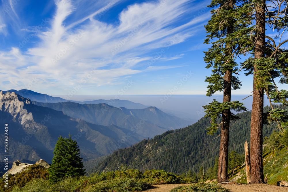 Landscape in Sequoia National Park in Sierra Nevada mountains on a sunny day; smoke from wildfires visible in the background, covering the valley; - obrazy, fototapety, plakaty 