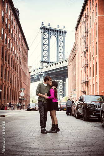 Photography Couple kissing on cobbled street amidst buildings against Manhattan Bridge in ci