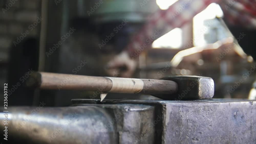 Blacksmith getting a red-hot top of the axe. Hammer in focus Blacksmith getting a red-hot top of the axe. Hammer in focus
