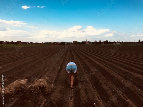 Blue sky over farm with sexy girl bending over field
