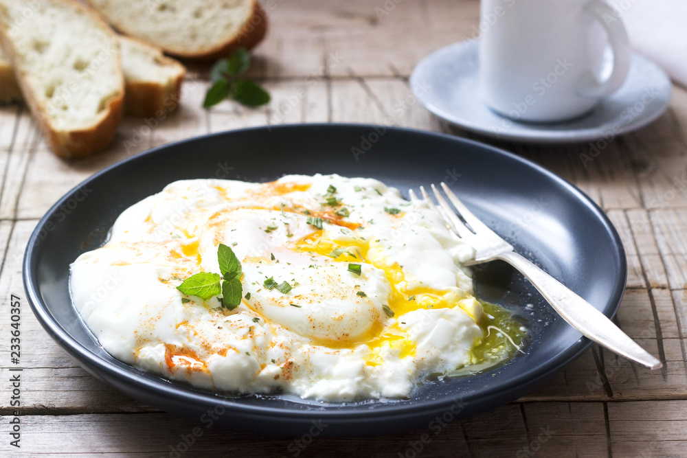 Cilbir, poached egg in yogurt with spiced butter and herbs, served with bread and a cup of coffee. Cilbir, poached egg in yogurt with spiced butter and herbs, served with bread and a cup of coffee.