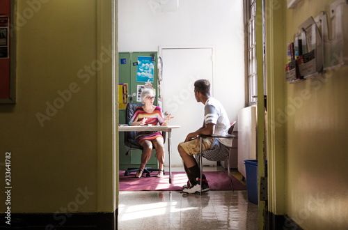 Principal talking with teenage boy while sitting in office