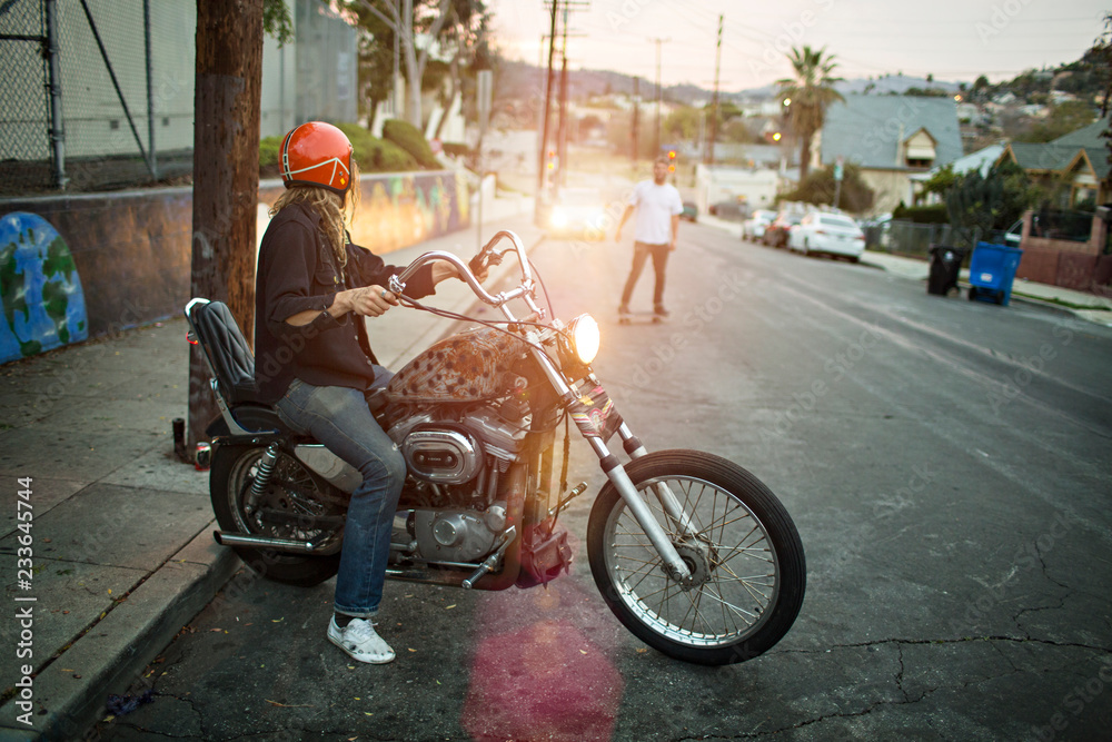 Obraz premium Man with motorcycle looking at friend on road