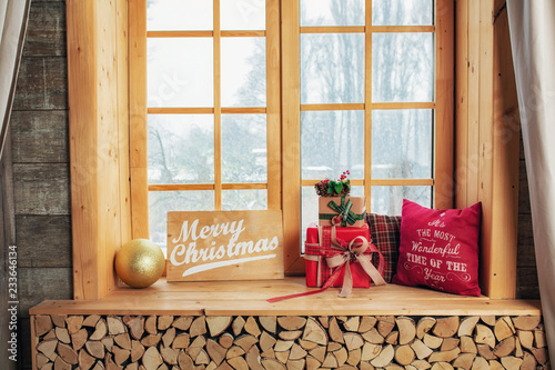 Fotografija Cozy and frost winter day: christmas decoration on wood windowsill and snow landscape from outside