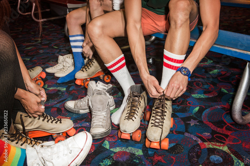 Fotografie Low section of people tying roller skates on multi colored floor