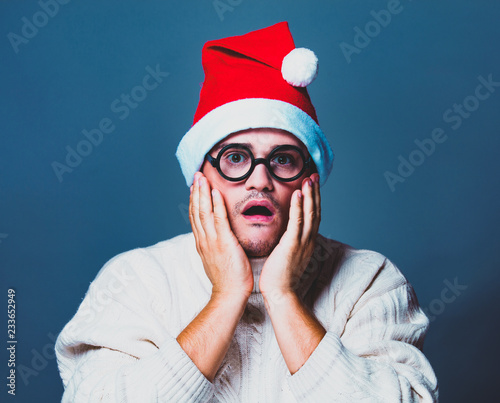 Funny man in red Christmas hat and white sweater and glasses