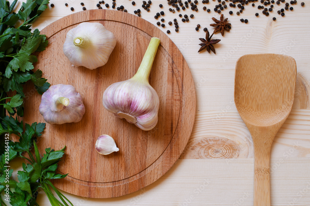 Food background with fresh greens, spices and garlic on wooden plate with bamboo spoon Food background with fresh greens, spices and garlic on wooden plate with bamboo spoon