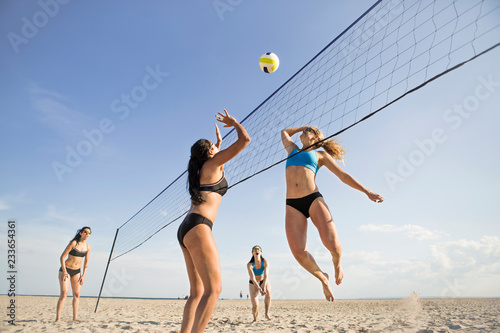 Photos Low angle view of female friends playing volleyball at beach on sunny day