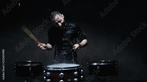 The drummer on the drum wooden sticks and water drops flying in all directions. photo