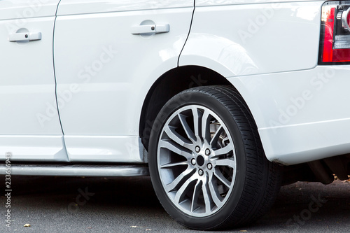 White SUV car close-up side view of the rear wheel with a wing and doors with handles, nobody. © Александр Беспалый