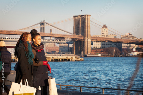 Photography Happy friends standing by river against Brooklyn Bridge