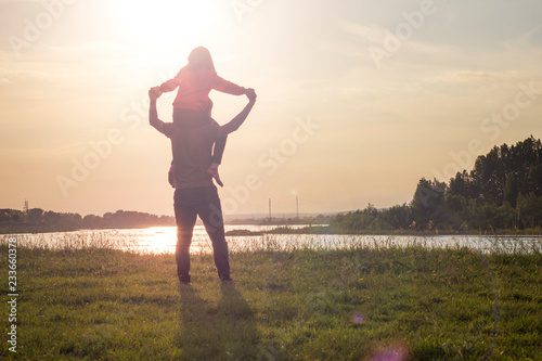 Εκτύπωση καμβά Rear view of father carrying daughter while standing at lakeshore during sunset