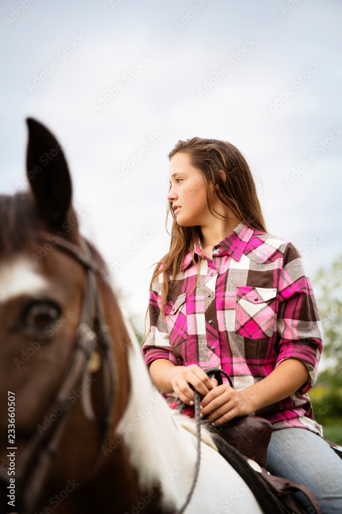 Obraz premium Teenage girl looking away while sitting on horse against sky