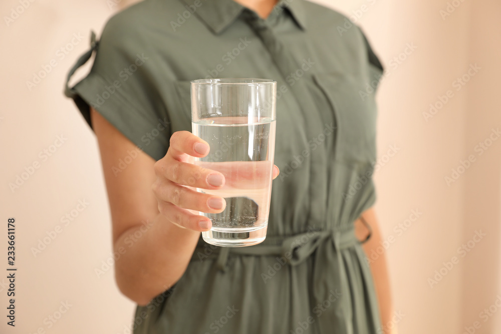 Woman holding glass with water on light background, closeup Woman holding glass with water on light background, closeup