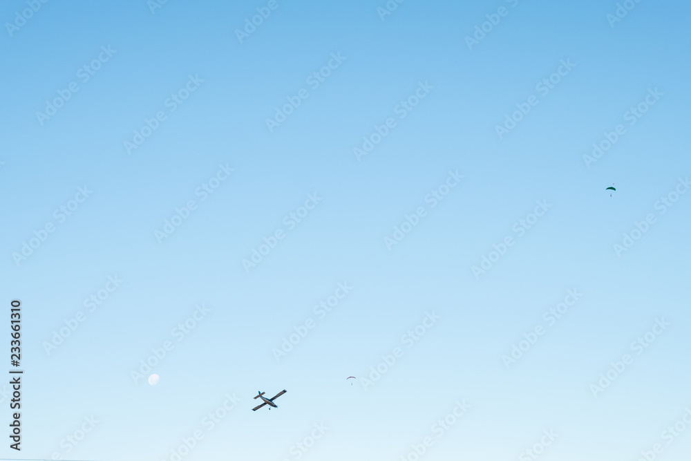 View of the blue sky with airplane and people are skydiving.