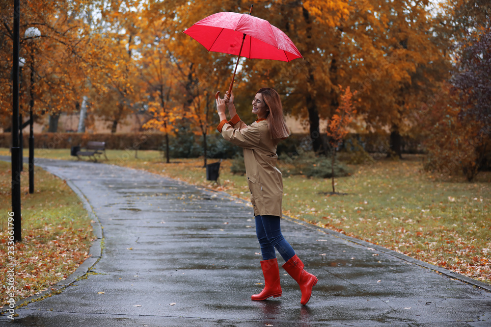 Obraz premium Woman with umbrella taking walk in autumn park on rainy day