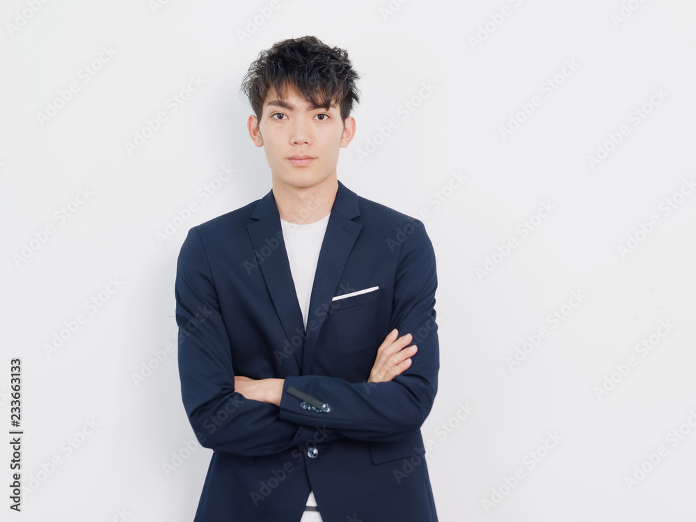 Portrait of handsome Chinese young man in dark blue leisure suit posing against white wall background. Looking at camera with arms crossed. Portrait of handsome Chinese young man in dark blue leisure suit posing against white wall background. Looking at camera with arms crossed.