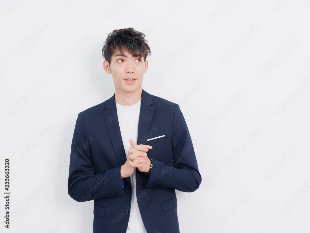 Portrait of handsome Chinese young man in dark blue leisure suit posing against white wall background. Fingers crossed and looking away. Portrait of handsome Chinese young man in dark blue leisure suit posing against white wall background. Fingers crossed and looking away.