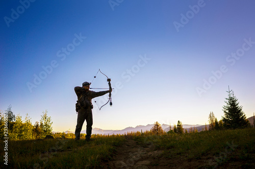Photography Hunter hunting with bow and arrow while standing on field against clear sky