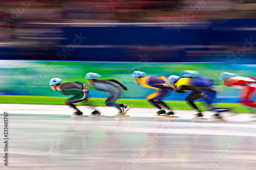 Side view of ice-skaters in skating ring