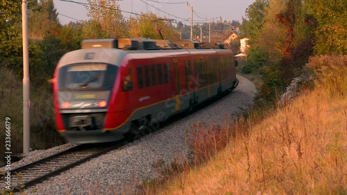 A train passes by a curved train track on a bright autumn fall day. photo
